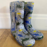 Pair of wellington boots with dinosaur pattern on a wooden floor.