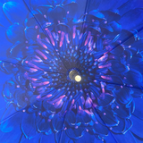 A close-up view from underneath of a vibrant blue flower-patterned umbrella, showing layered petals and a central metal handle.