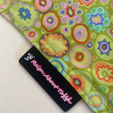 Colorful fabric with circular patterns and a brand label on a white background