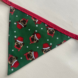 Green fabric triangle with dog pattern and red trim on a white background