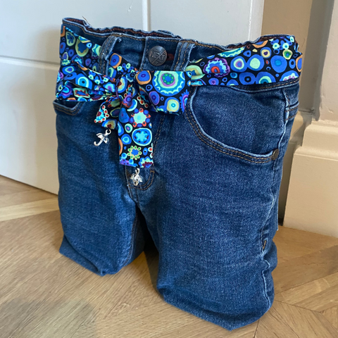 Blue jeans door stop with a decorative blue belt on a wooden floor.