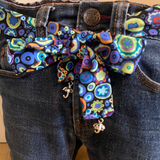 Blue jeans door stop with a colorful patterned belt on a wooden floor.