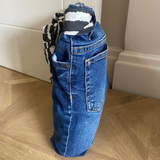 Blue jeans door stop against a white wall on a wooden floor.