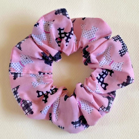 Pink scrunchie with black patterns on a light yellow background