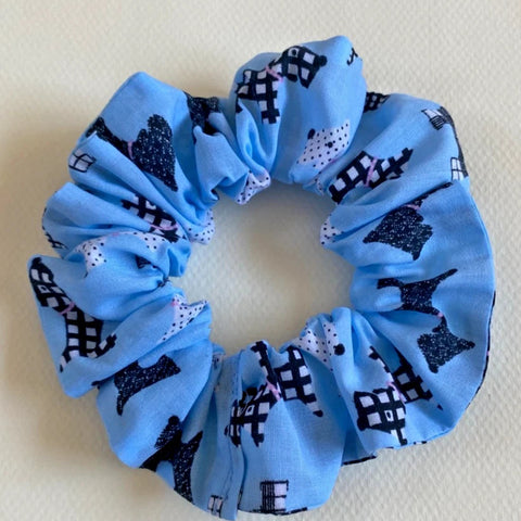 Blue scrunchie with black and white pattern on a beige background
