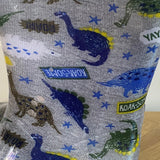 Gray fabric with dinosaur patterns and 'ROAR-SONE' labels on a wooden surface.