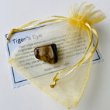 Tiger's eye crystal in a yellow drawstring bag with information card on a white background