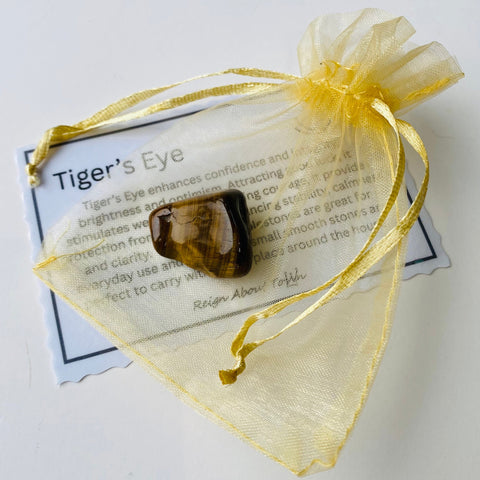 Tiger's eye crystal in a yellow drawstring bag with information card on a white background